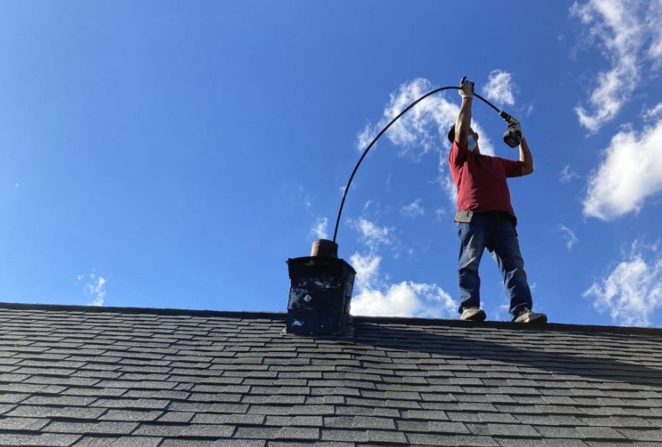 Certified chimney technician inspecting and cleaning a fireplace chimney in North Carolina.